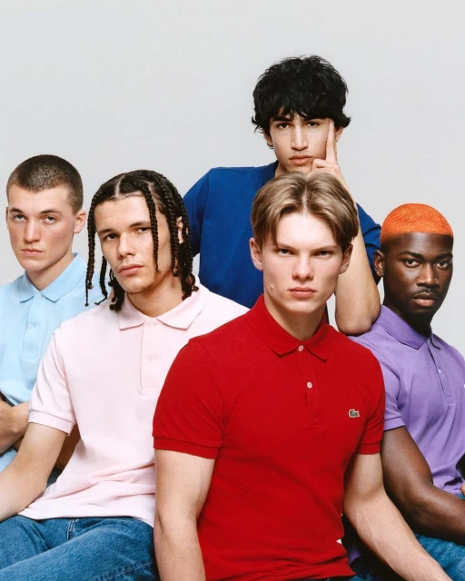 Group portrait of five young men in blue jeans wearing various colored polo shirts in front of a white background in a studio.