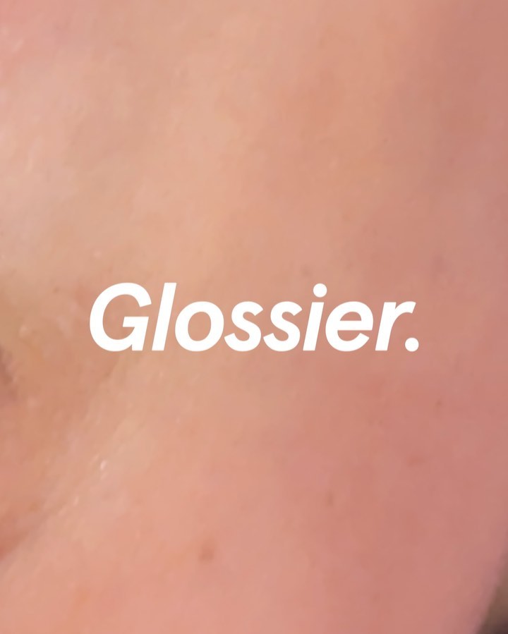 Close-up macro image showing skin texture with the white text Glossier overlaid.