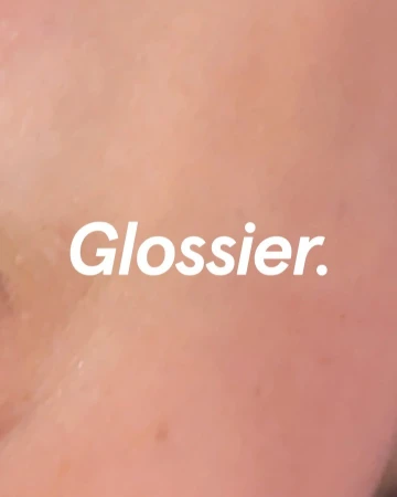 Close-up macro image showing skin texture with the white text Glossier overlaid.