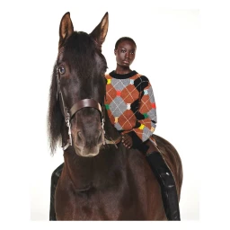 Black woman seated on a dark brown horse wearing an argyle sweater and black leather boots against white background