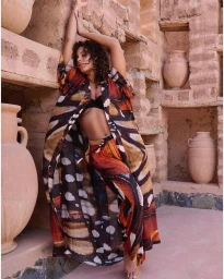 Woman in patterned robe leaning against a textured earthen wall with pottery by photographer Fumie