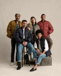 Group of five diverse models wearing winter outerwear including puffer jackets and vests in a studio portrait.