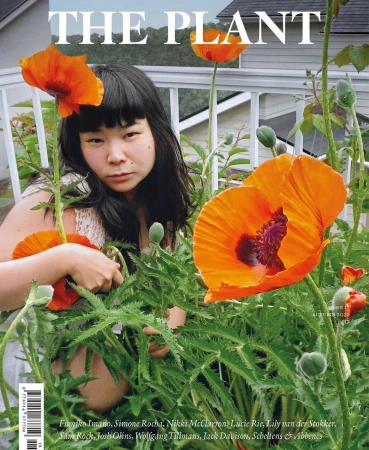 Magazine cover featuring a woman among tall green plants with large bright orange poppy flowers in a garden.