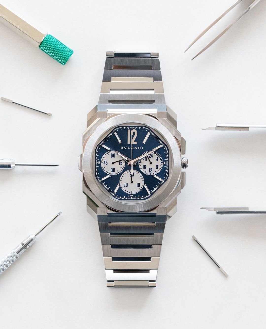 Elegant Bulgari Octo Finissimo watch with a stainless steel bracelet, set against a clean white background with watch repair tools.