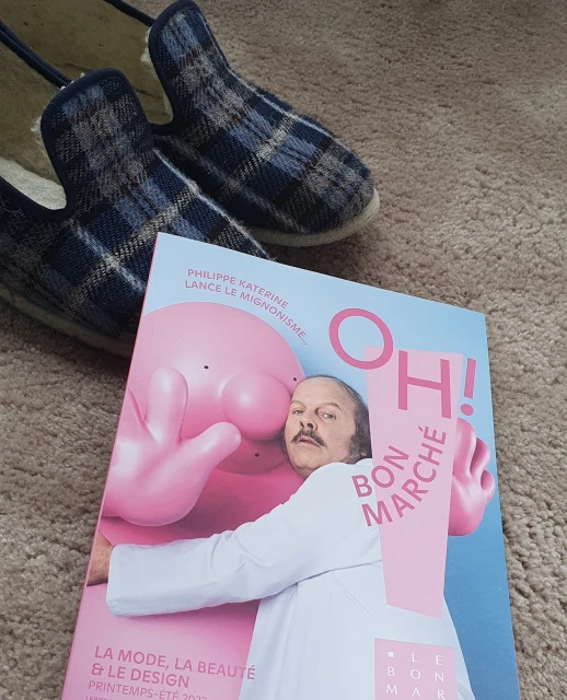 Magazine cover featuring a person with a pink cartoon character, indoor slippers, and a beige carpet in the background.
