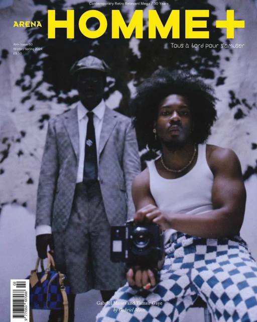 Arena Homme+ magazine cover featuring two men, one holding a camera, in an indoor studio setting with patterned backgrounds and clothing.