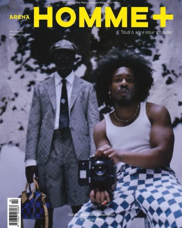 Arena Homme+ magazine cover featuring two men, one holding a camera, in an indoor studio setting with patterned backgrounds and clothing.