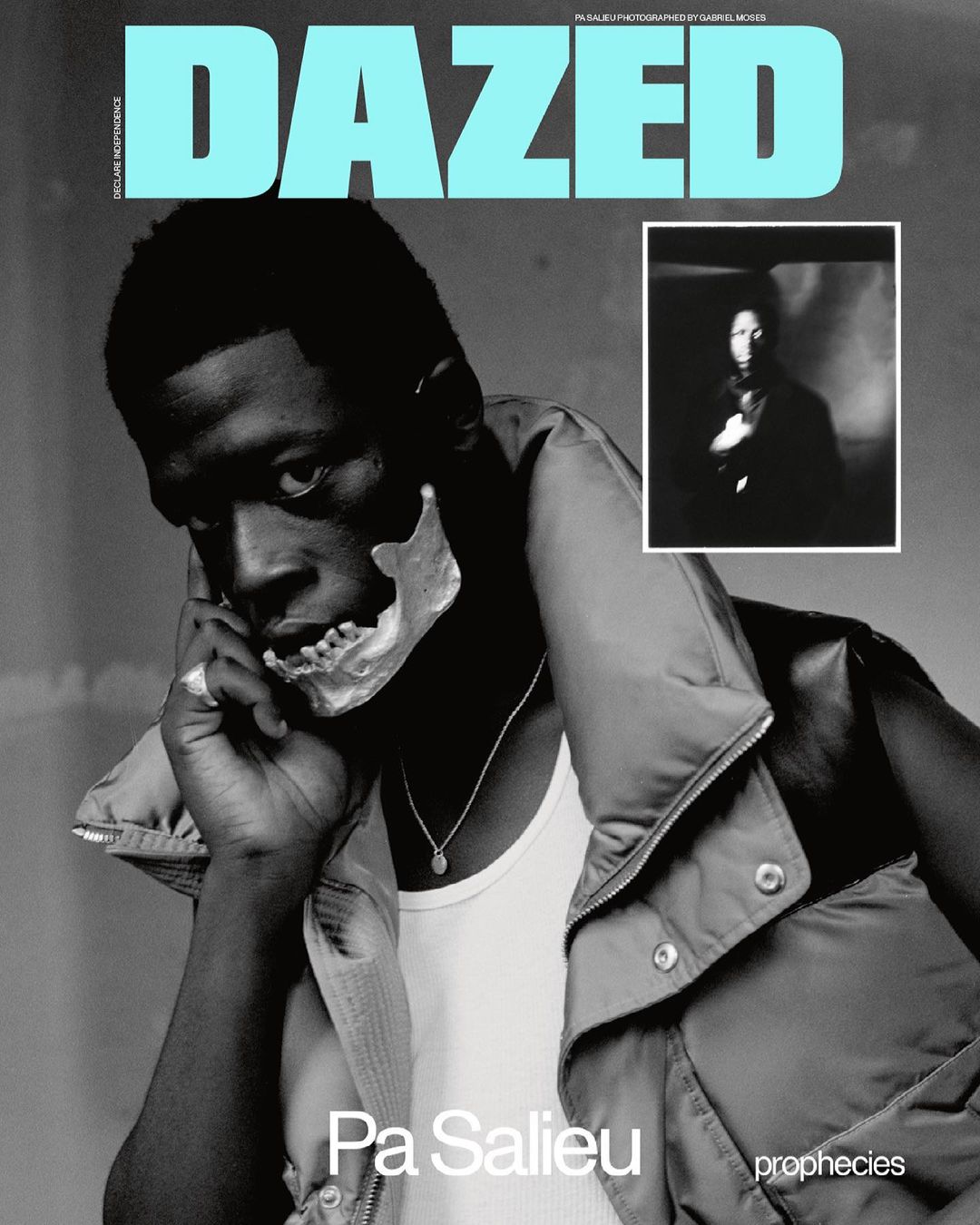 Magazine cover featuring African male in vest, white tank top, and prosthetic skull part over mouth, Dazed text logo at top.  