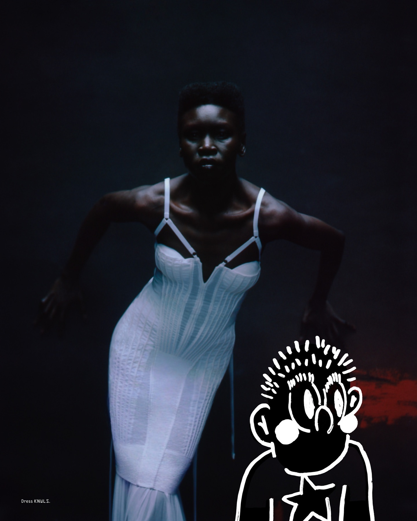 An African woman poses in a long white dress in a dark photo studio setting. The image also features a stylized cartoon character.