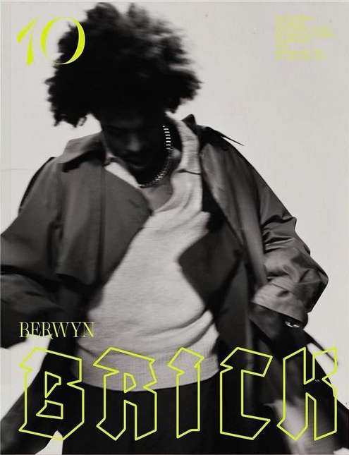 Magazine cover featuring a person in a trench coat with an afro hairstyle, set against a light background with neon yellow text elements.