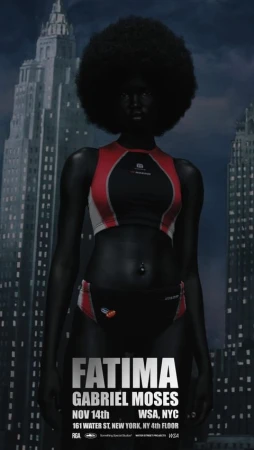 Full body portrait of an adult female fashion model in red and black swimwear, standing against an urban background with tall buildings.