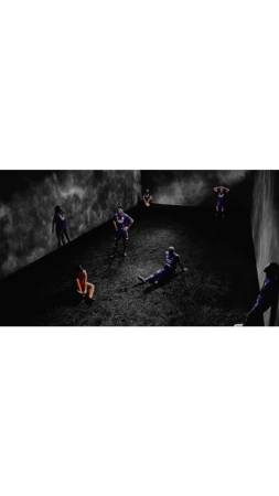 Multiple athletes in sports uniforms scattered in a dimly lit, minimalist indoor space with dark, cloudy background, creating a dramatic scene.