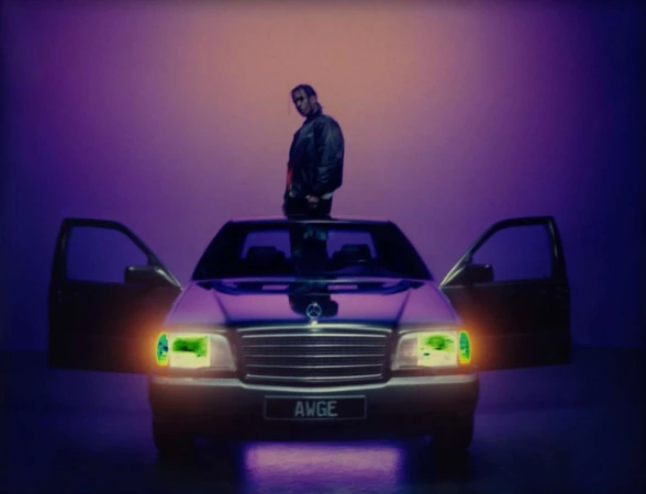 ASAP Rocky standing on top of a car with open doors against a purple background, photographed by Gabriel Moses.