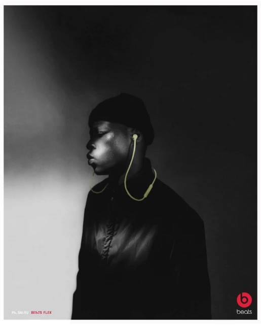Black and white portrait of a young adult male with headphones and a beanie, set against a dark backdrop with studio lighting.