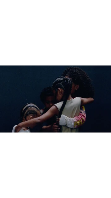 Four children huddle together in a close embrace against a dark background, showcasing a heartwarming moment of togetherness and warmth.