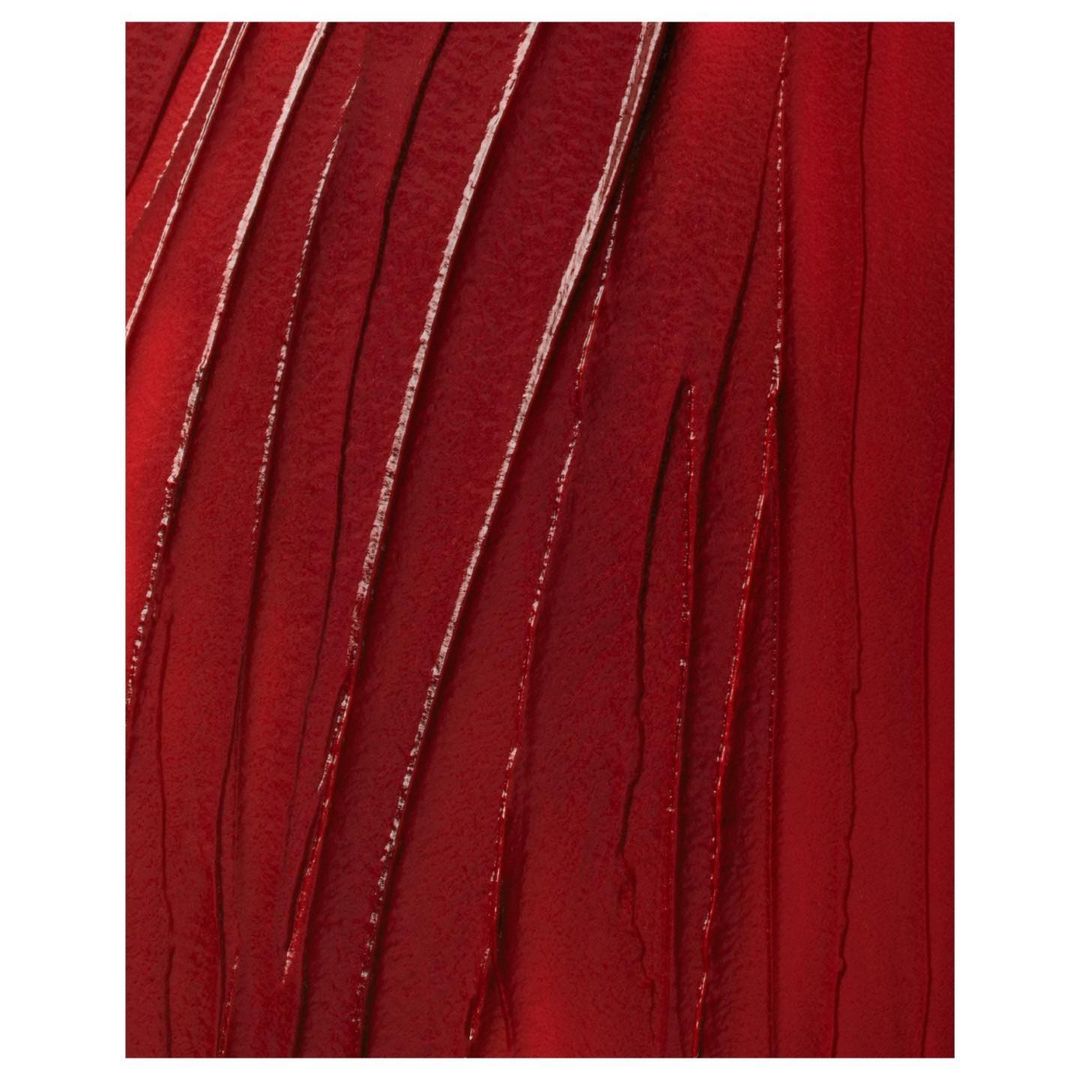 Close-up of vibrant, textured smear of deep red lipstick or lip gloss, featuring glossy ridges and an inviting color palette.