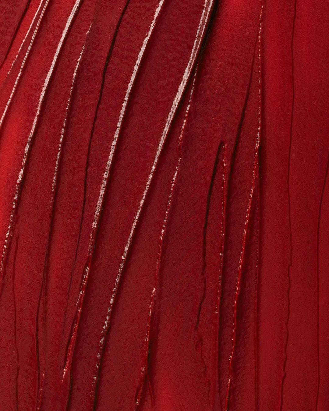 Macro texture of vibrant, glossy red lipstick swatches shows creamy consistency, light reflection, and rich pigmentation, good for beauty concept.