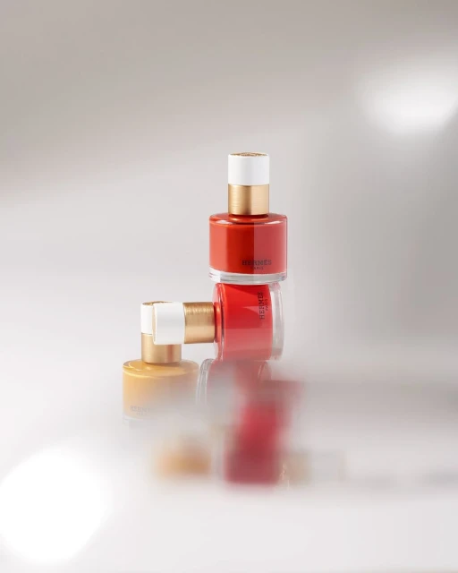 Still life shot of three nail polish bottles stacked against a blurred white background for beauty and cosmetics advertising.