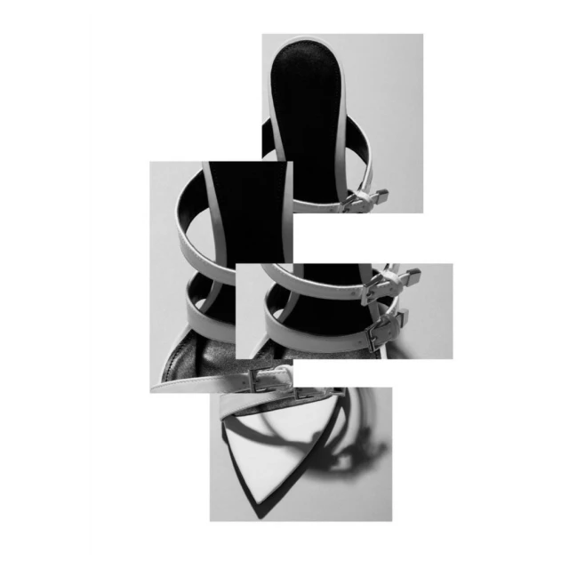 Monochrome fashion product shot features a deconstructed sandal with buckles and straps on a white backdrop, creating a minimalist aesthetic.