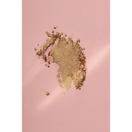 Close-up of golden eye shadow powder on a pale pink background, with soft lighting and subtle gradient adding depth to the scene.