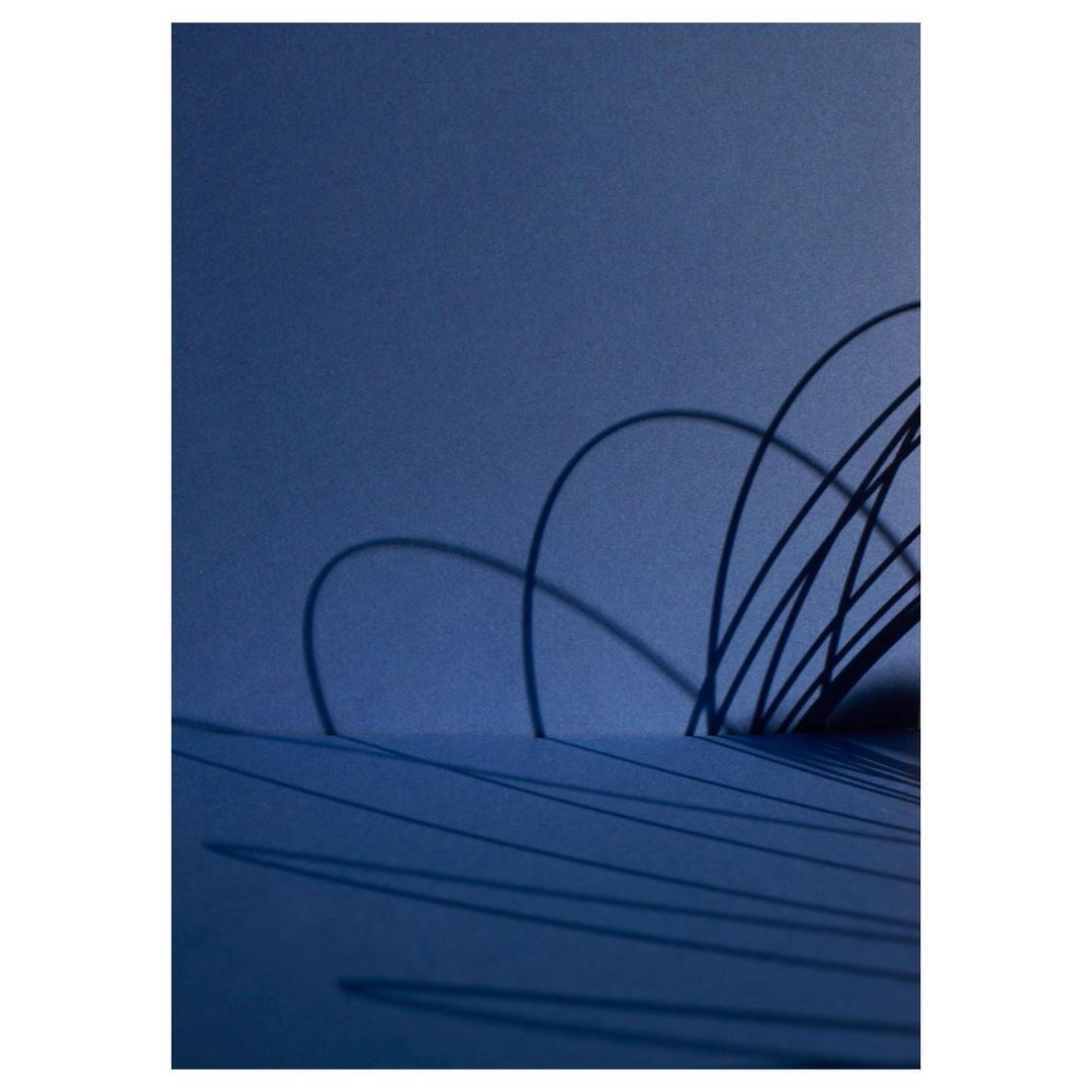 Abstract still life featuring blue gradient background with arched black line objects and shadows, creating a minimalist composition.