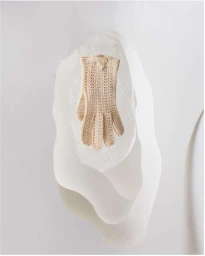 Cream crocheted glove resting on abstract white layered paper forms against a pale background