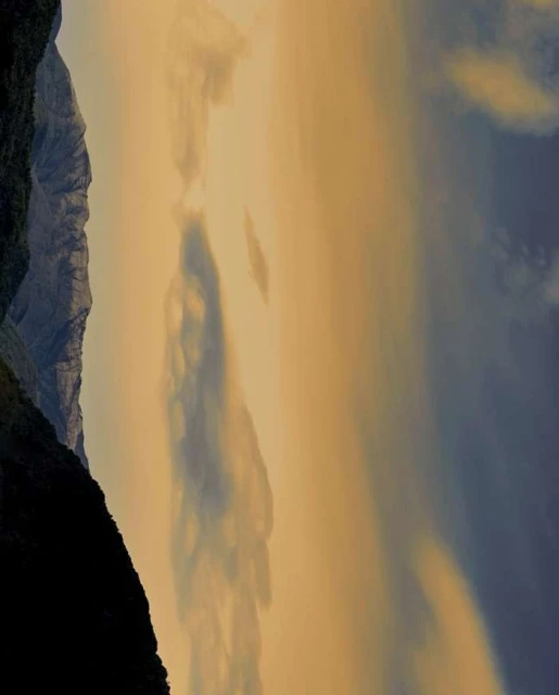 Scenic view of mountains and cloudy sky, creating a soft, golden atmosphere in a landscape-oriented composition.