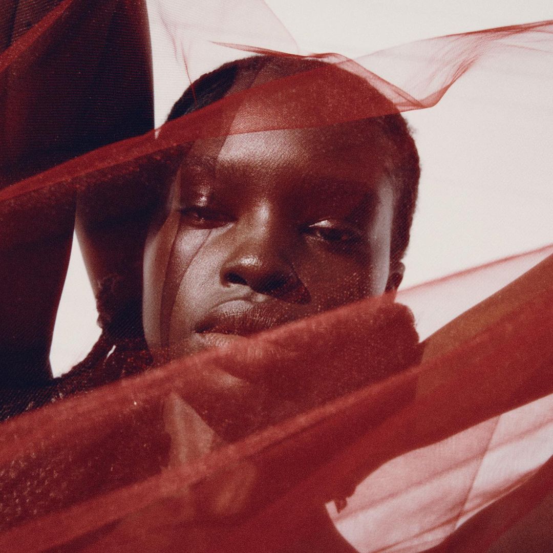 Close-up portrait of a Black woman framed by draped sheer red fabric by Garrett Naccarato