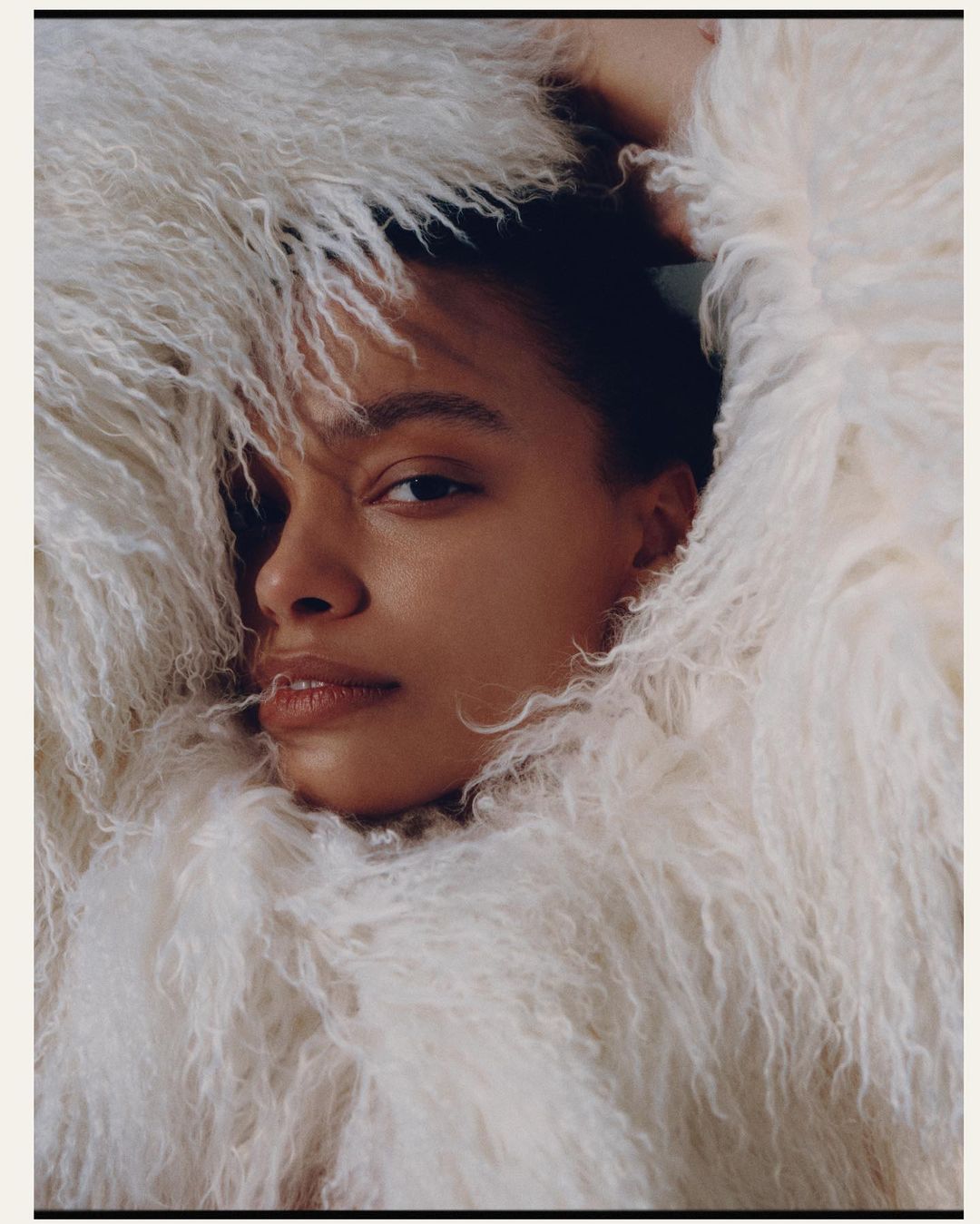Close-up portrait of a woman wrapped in a fluffy white textured faux fur coat framing her face by photographer Garrett Naccarato.
