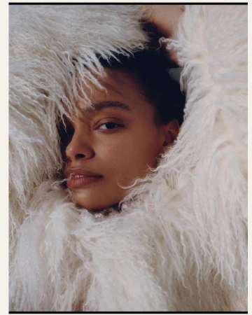 Close-up portrait of a woman wrapped in a fluffy white textured faux fur coat framing her face by photographer Garrett Naccarato.