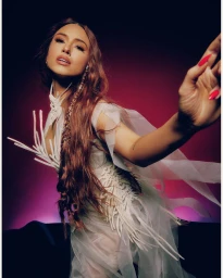 Portrait of a woman with long red hair wearing a structured white dress against a dark gradient background by Garrett Naccarato