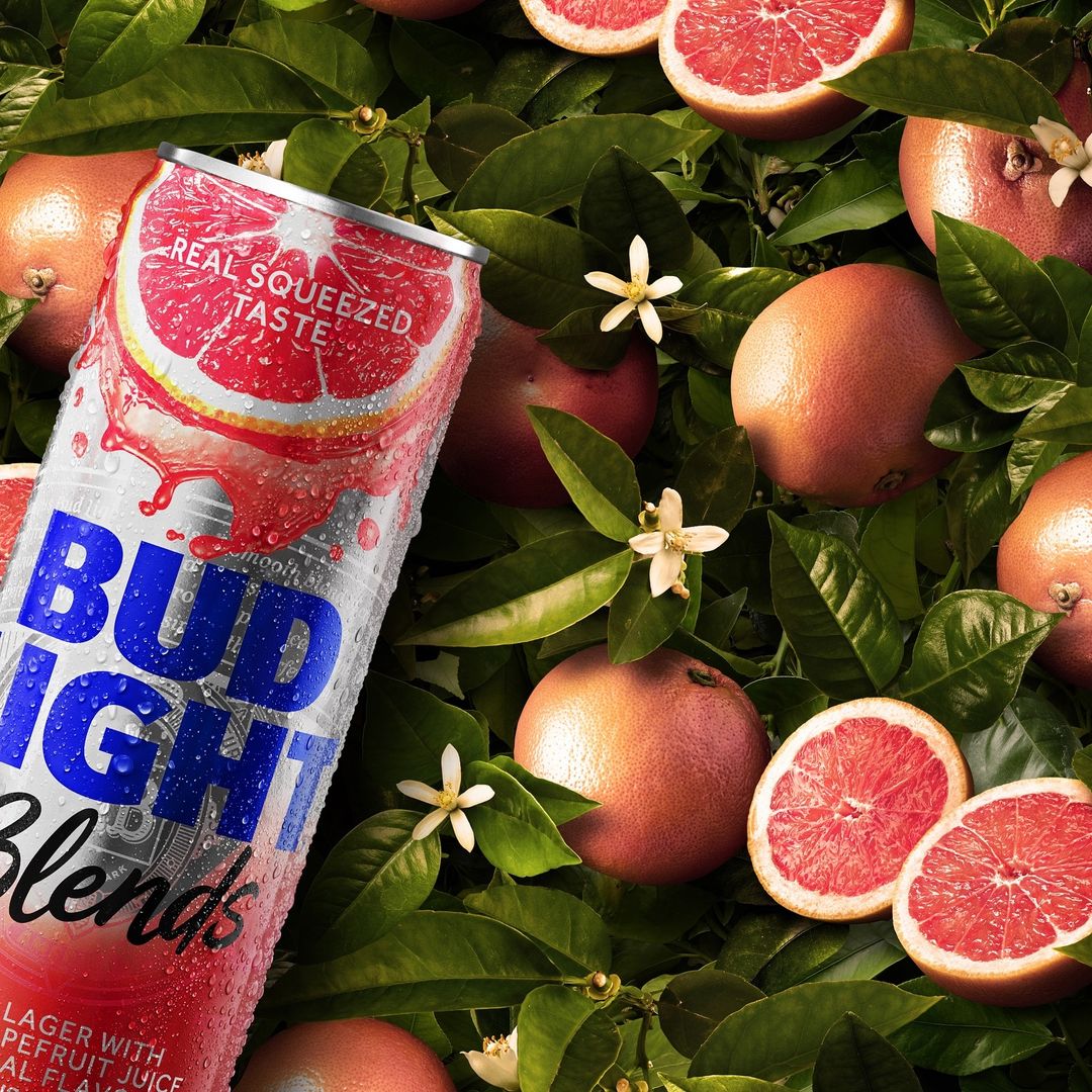 A can of Bud Light Seltzer Blends Grapefruit stands out against a background of grapefruit, leaves, and blossoms, hinting at citrus flavors.
