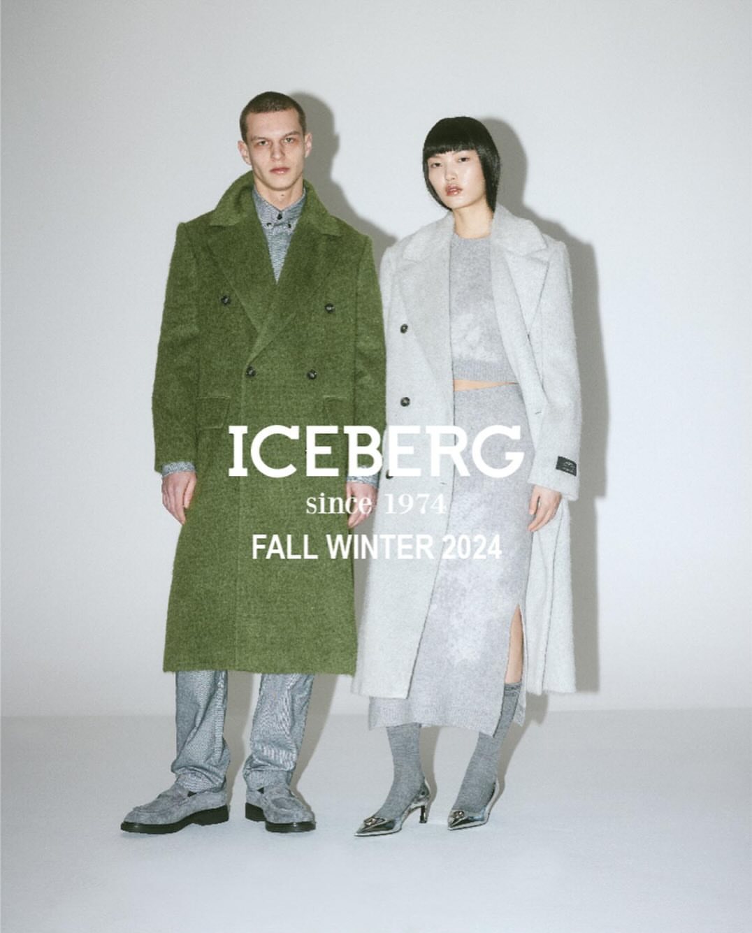 Fashion editorial featuring a male and female model wearing ICEBERG Fall/Winter 2024 collection, posing in a light grey studio.