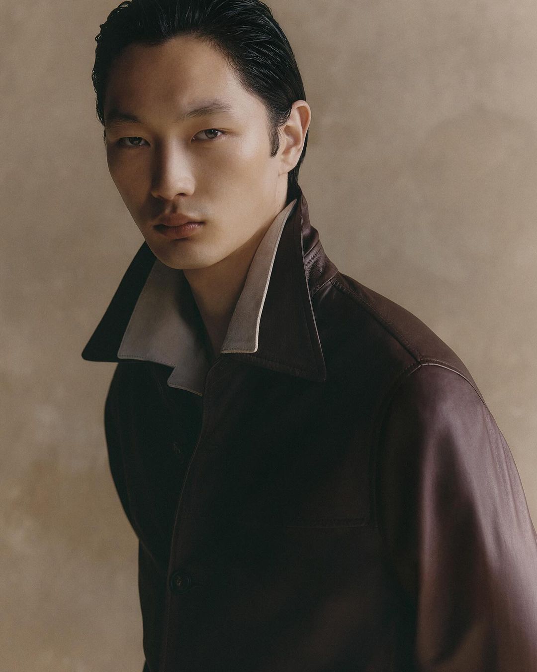 Portrait of an East Asian male model wearing a dark leather jacket with a contrasting collar, captured by Gautier Pellegrin in Milan.