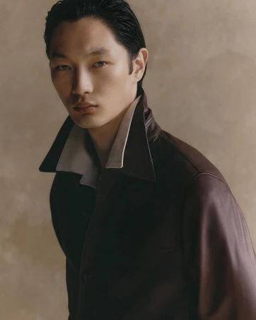 Portrait of an East Asian male model wearing a dark leather jacket with a contrasting collar, captured by Gautier Pellegrin in Milan.
