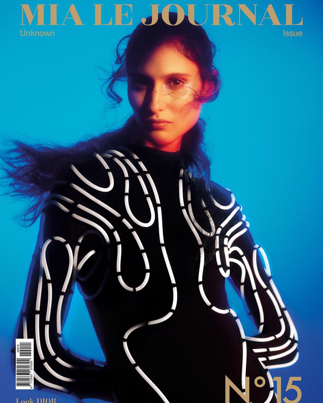 Model in a black long-sleeve top with white abstract piping against a vibrant blue background with warm red rim lighting.