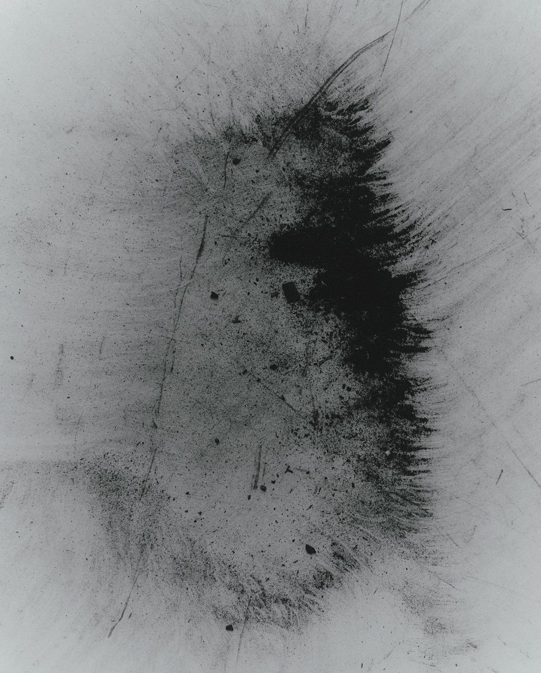 Monochrome abstract art image featuring a central dark smoky formation on a textured light background, creating a striking contrast.