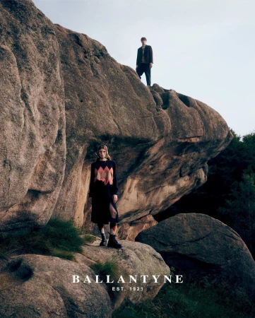 Two models standing on rugged rocky formations outdoors under an open sky, captured by Gautier Pellegrin in Milan.