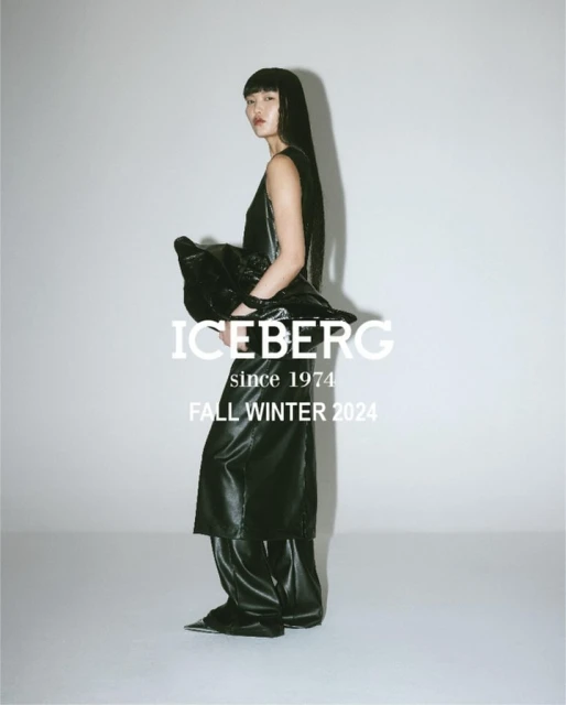 A woman poses in black Iceberg Fall/Winter 2024 fashion in a studio with a white backdrop. She wears a dark top, long skirt and pants.