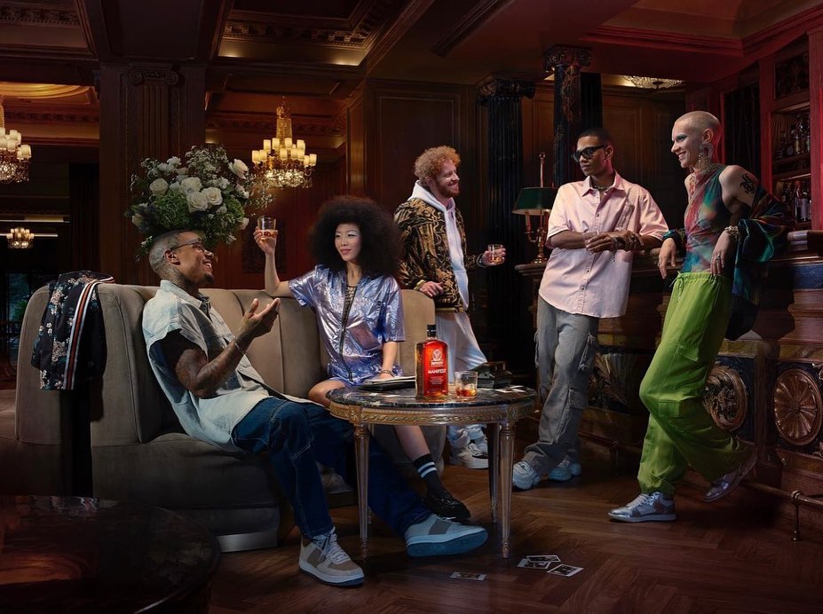 Group of diverse young adults socializing at a bar, holding drinks, with a bottle on the table, and elegant interior details.