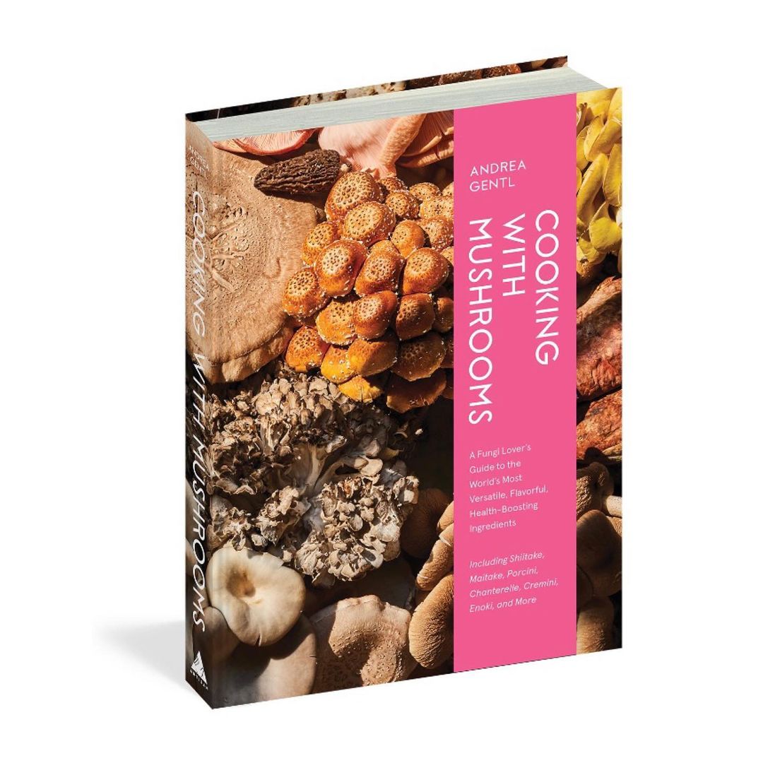 A cookbook featuring various types of mushrooms is displayed, with a pink spine and the title 'Cooking With Mushrooms' clearly visible.