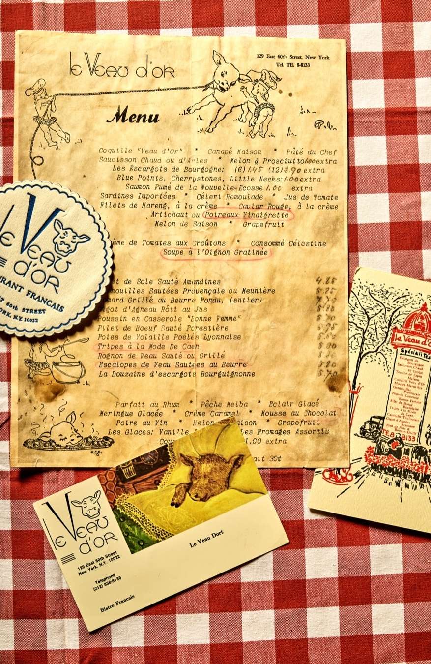 Vintage 'Le Veau d'Or' restaurant promotional materials: menu, card, coaster, and promotional mailer on a red-and-white tablecloth.