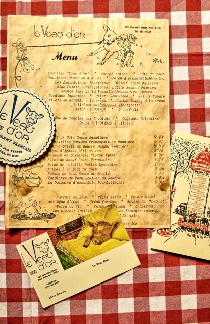 Vintage 'Le Veau d'Or' restaurant promotional materials: menu, card, coaster, and promotional mailer on a red-and-white tablecloth.