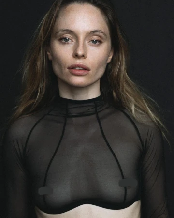 Portrait of a woman wearing a sheer black top against a dark background, photographed by Geoffrey Badner