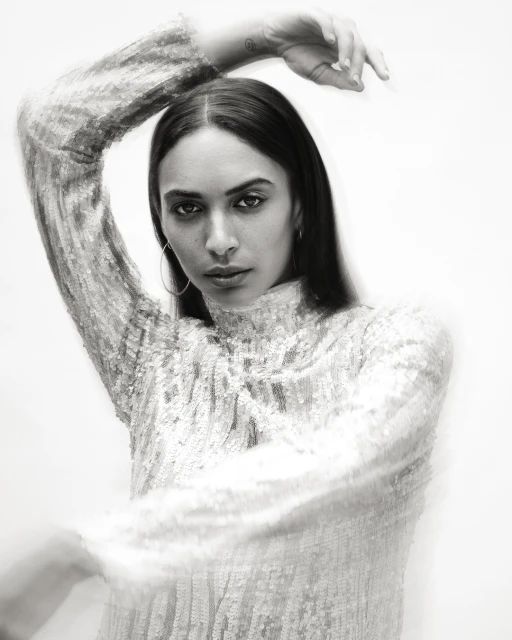 Monochrome portrait of a woman in a sequined top, gazing directly at the camera with soft-focus and shallow depth of field.
