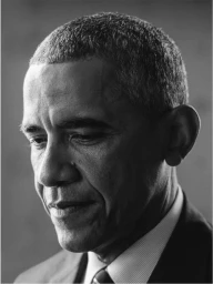 Close-up monochrome portrait of Barack Obama looking down thoughtfully in a suit and striped shirt