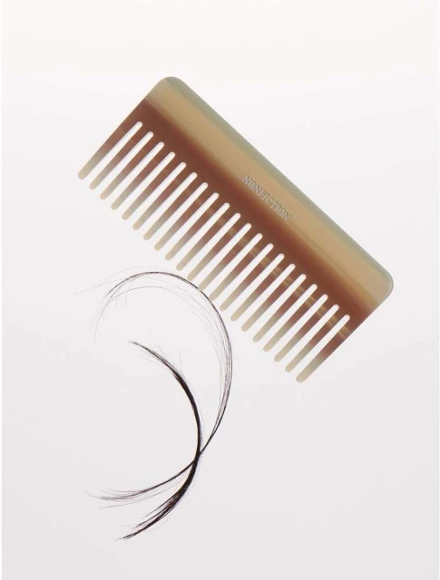 Horn comb with hair strands on a white background. Haircare product shot shows beauty and personal care objects.
