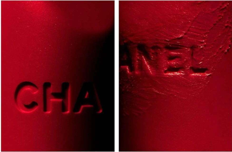 Close-up of the Chanel logo embossed in red lipstick. Macro shot of Chanel brand text, beauty product, red color, cosmetic, and lettering.
