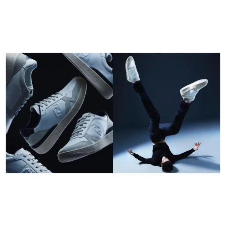 A split studio product shot showcases several light gray Fendi sneakers on a black backdrop next to a man balancing upside down on his head.