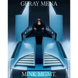 A person wearing sunglasses and a black outfit seated inside a futuristic blue vehicle with vertical wing-style doors.